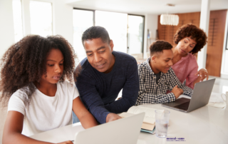 a father and mother help their teenaged son and daughter as they work on laptops