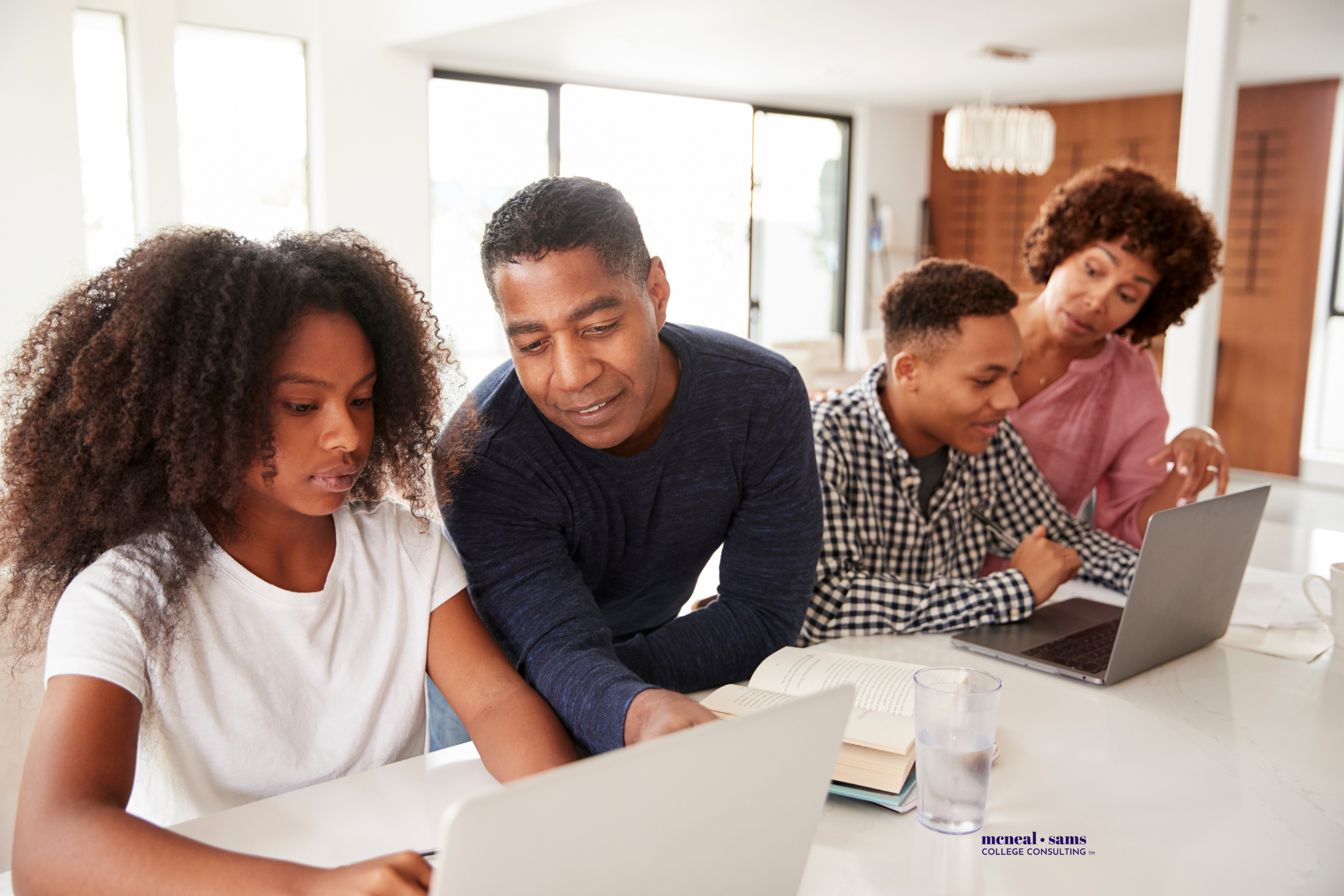 a father and mother help their teenaged son and daughter as they work on laptops