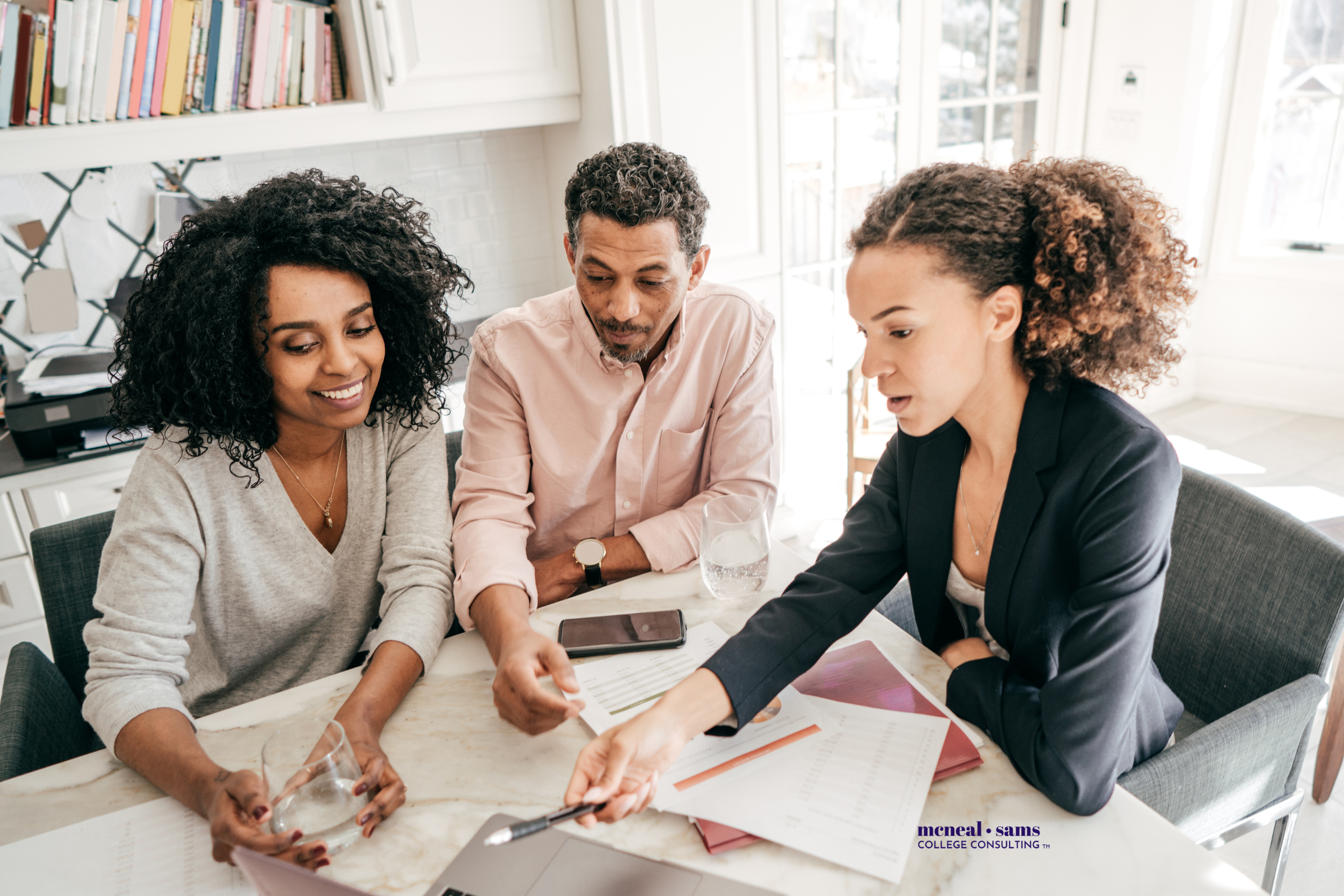 a husband and wife review documents with an advisor while seated at a table