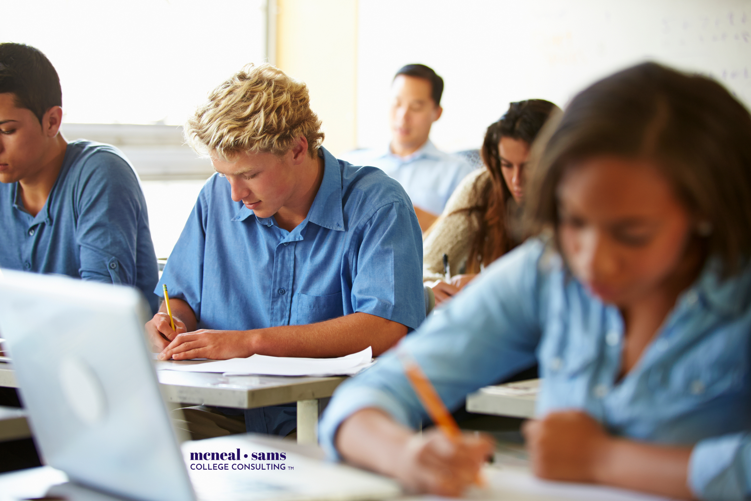 teenaged students seated at desks in a classroom taking a test