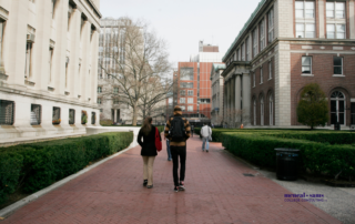 three students walk down on a college campus on a cold winter day