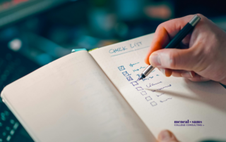 person is writing out a checklist in a notebook with a pen