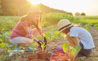 two teenage girls plant crops in a row in a field on a sunny day