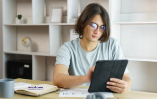 Teenager sits at a desk working on a tablet.