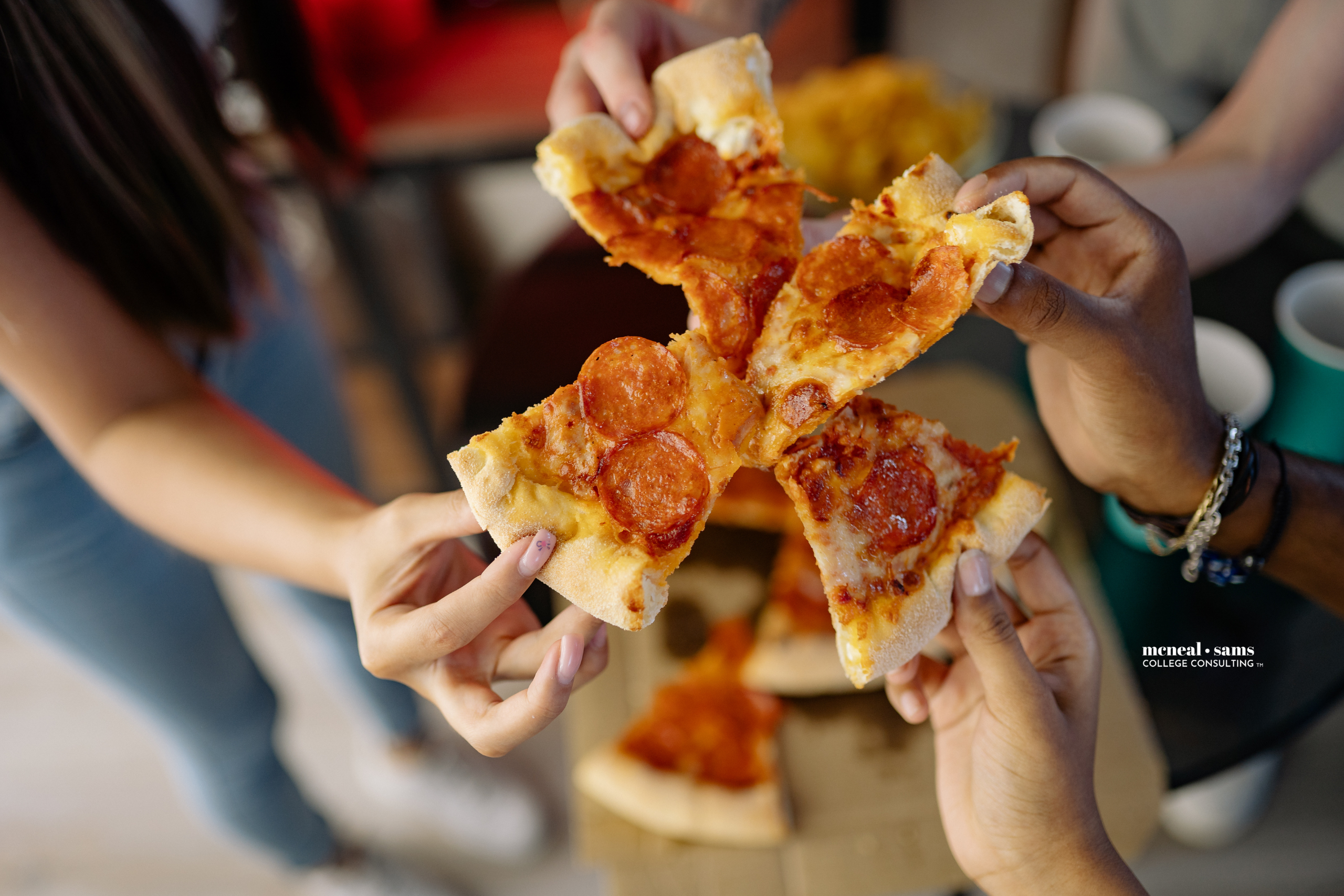 four people hold together four pieces and cheese and pepperoni pizza